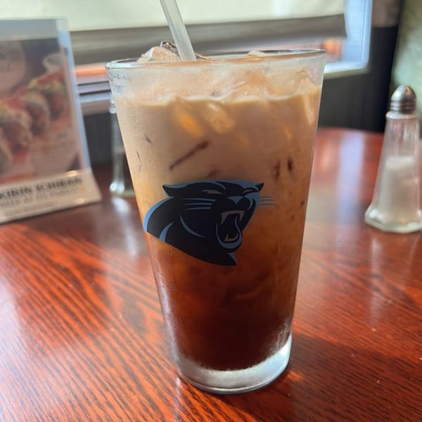 Iced tea with a Carolina Panthers logo on the glass, on a wooden table at Ginbu 401.