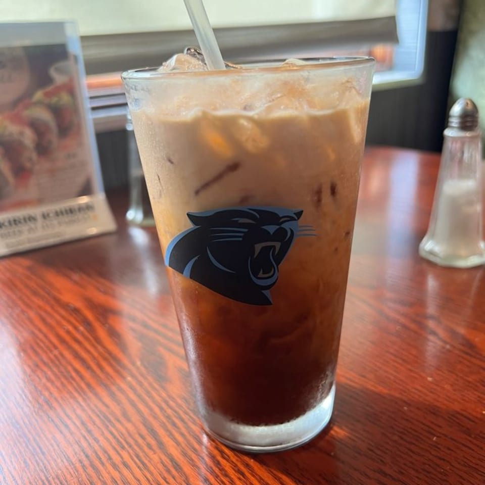 Iced tea with a Carolina Panthers logo on the glass, on a wooden table at Ginbu 401.